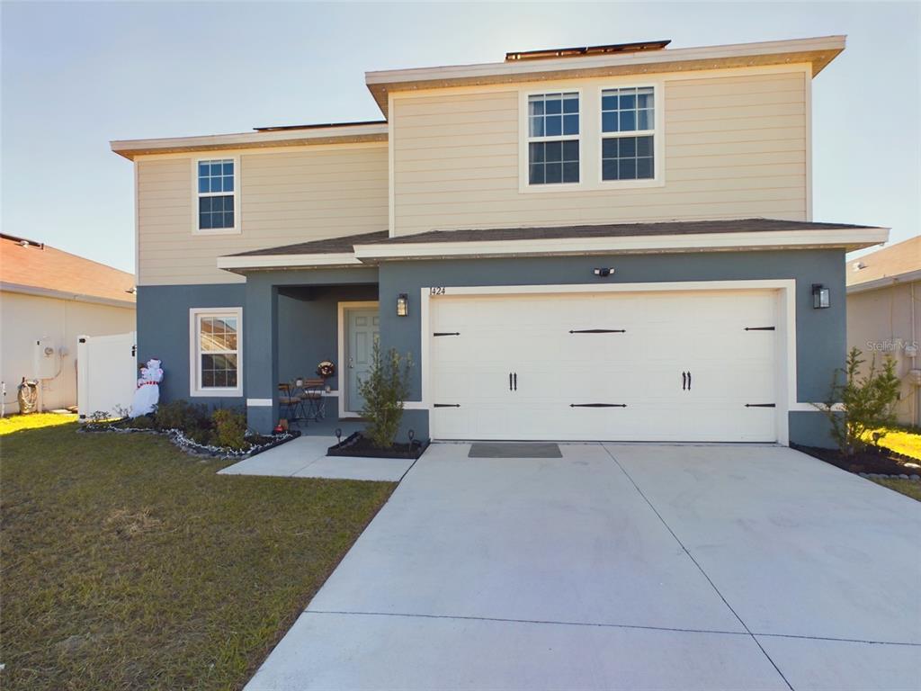 a front view of a house with yard and parking