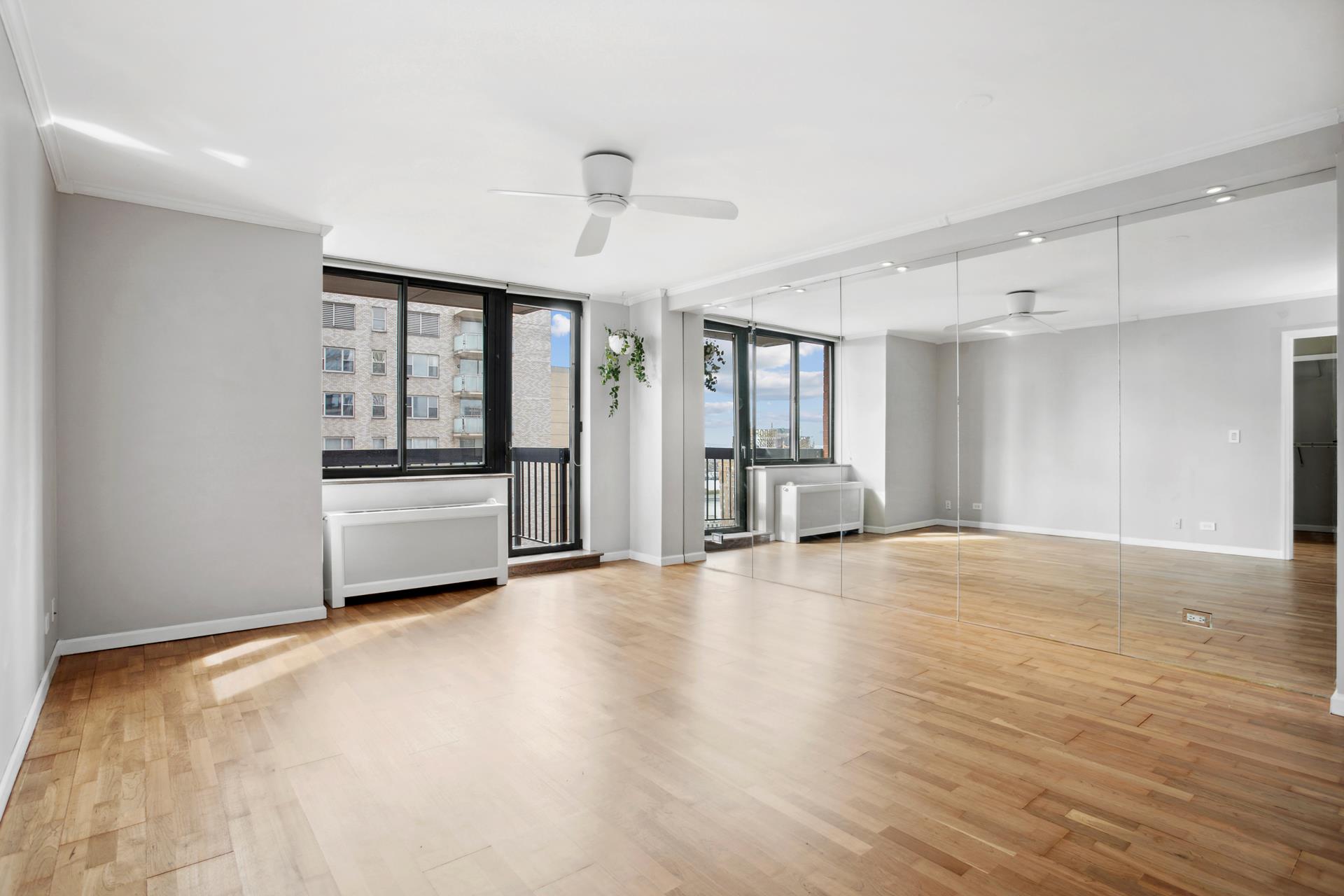 a view of an empty room with a window and wooden floor