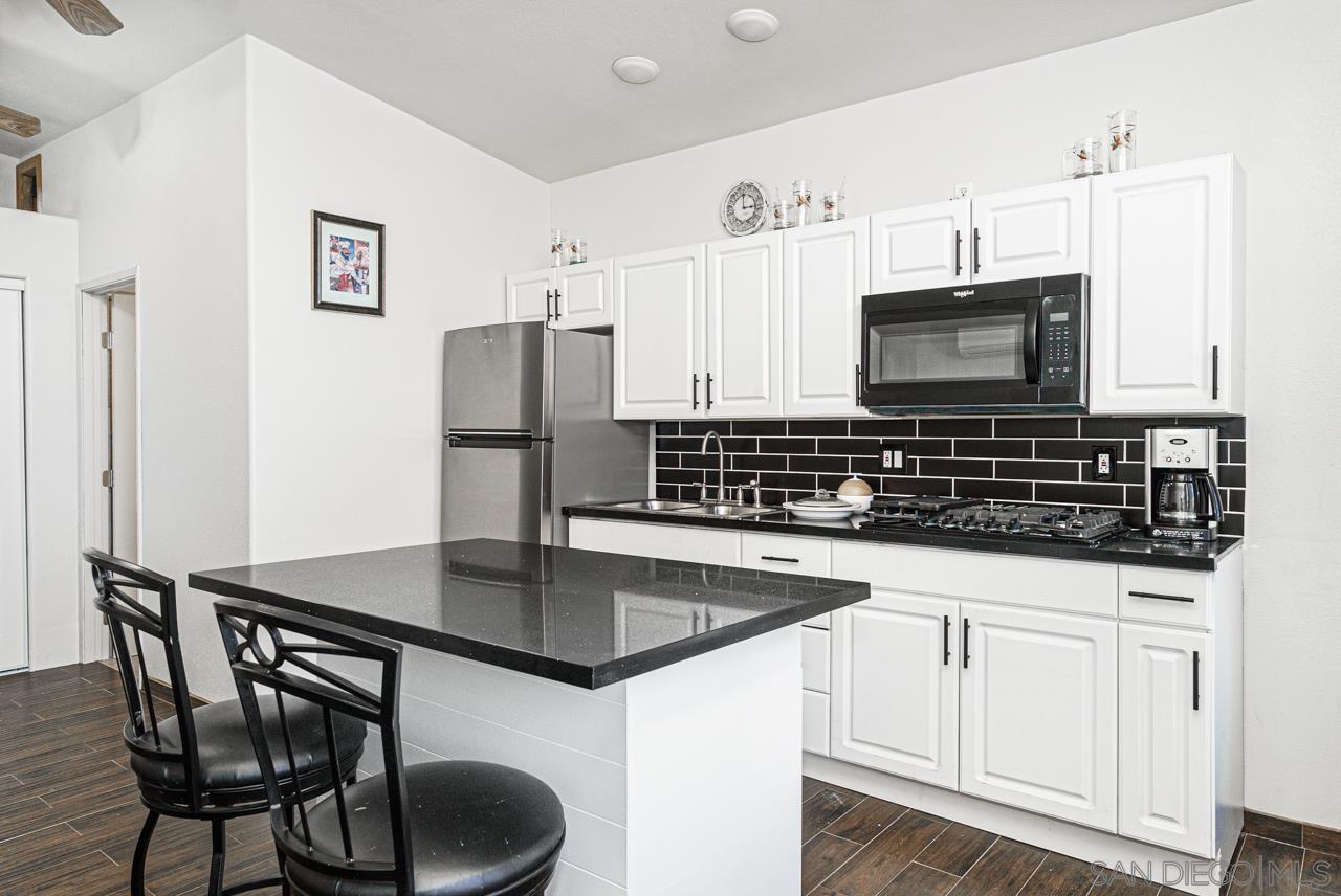 a kitchen with stainless steel appliances granite countertop a stove a microwave a sink and white cabinets