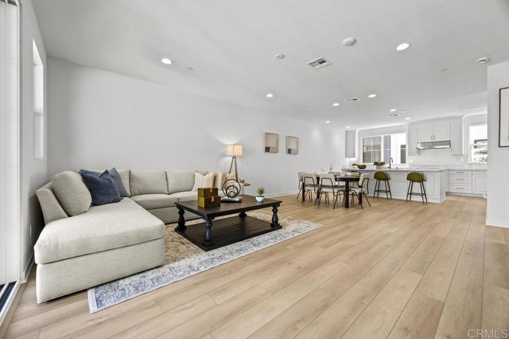 a living room with furniture and kitchen view with wooden floor