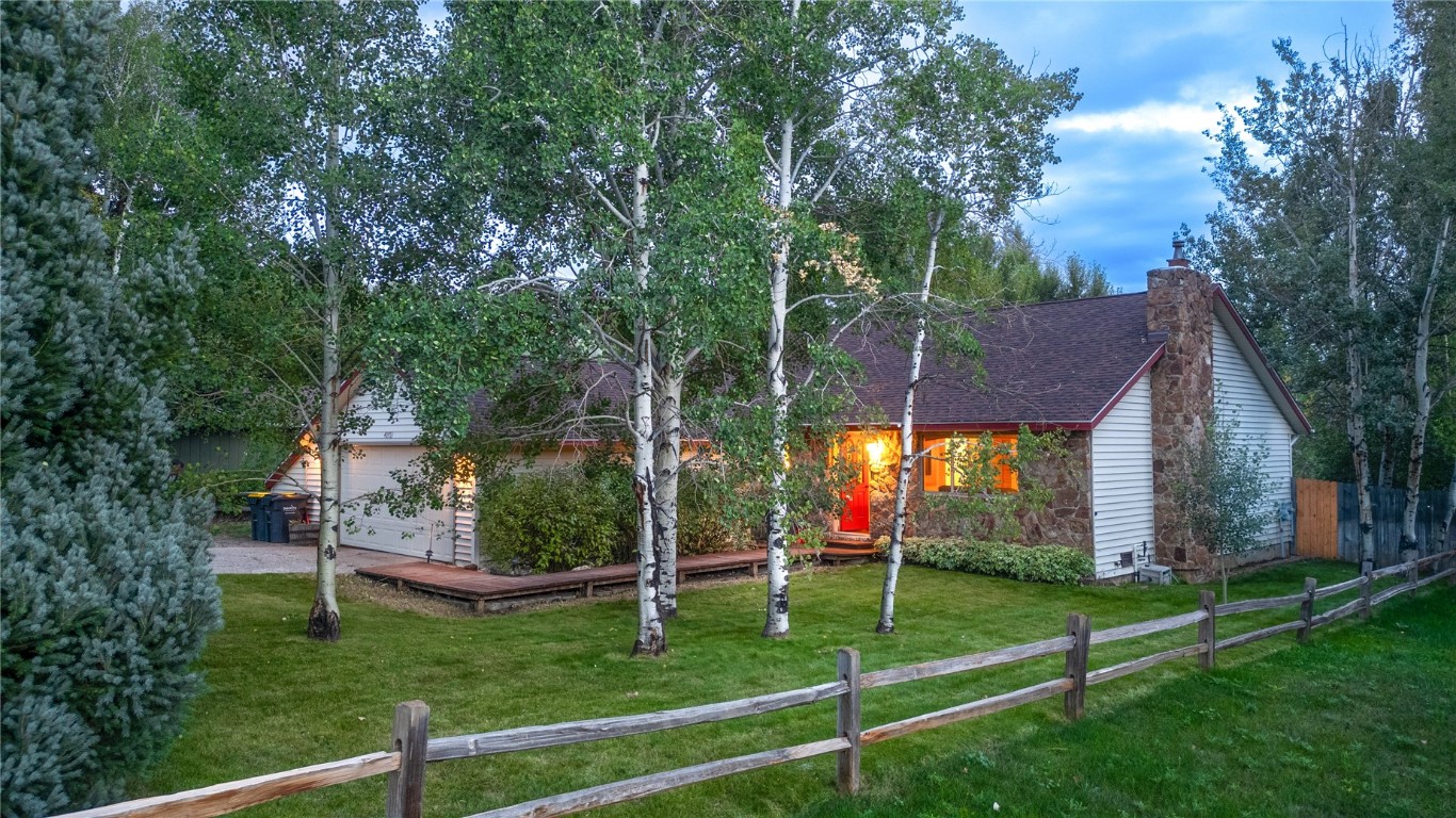 a view of an house with backyard and a tree