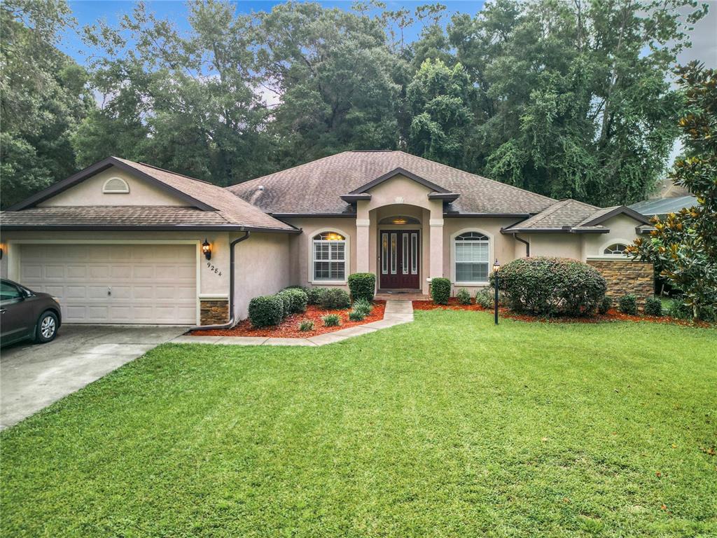 a front view of a house with a garden and trees