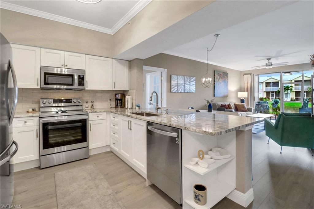 a kitchen with stainless steel appliances granite countertop a sink dishwasher stove and white cabinets with wooden floor