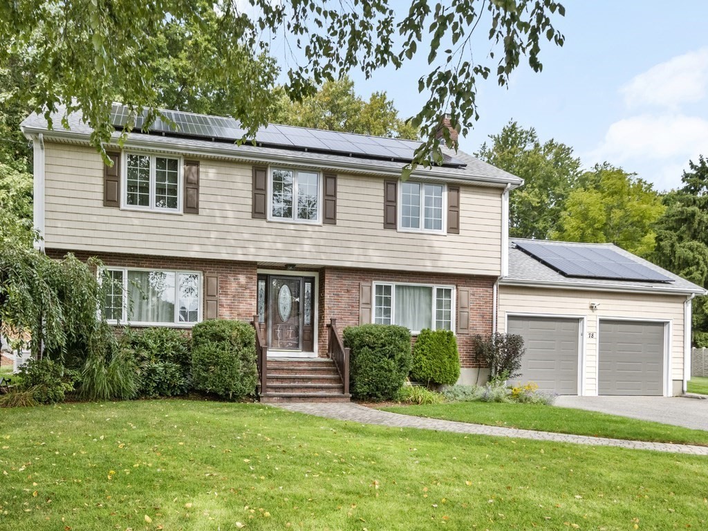 a house that has a big yard with potted plants and a large tree