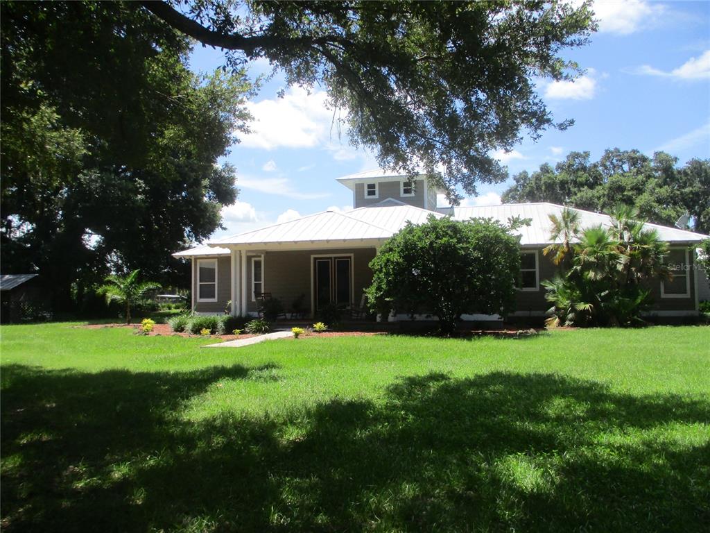 a view of a house with a big yard and large trees