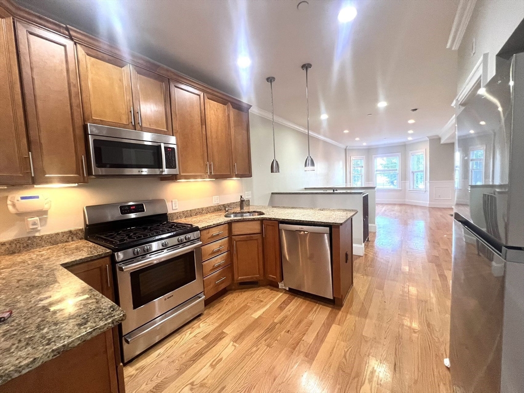 a kitchen with stainless steel appliances granite countertop wooden cabinets stove top oven and sink