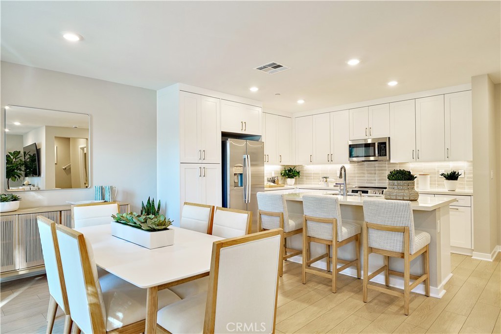 a kitchen with stainless steel appliances kitchen island granite countertop a dining table chairs and refrigerator