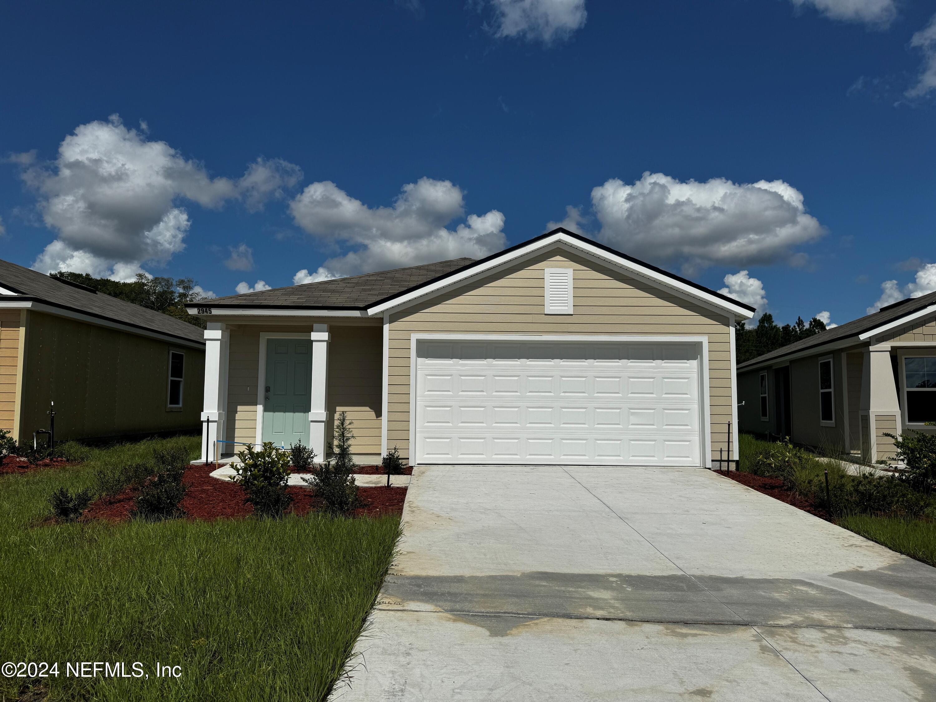 a front view of house with yard and trees in the background