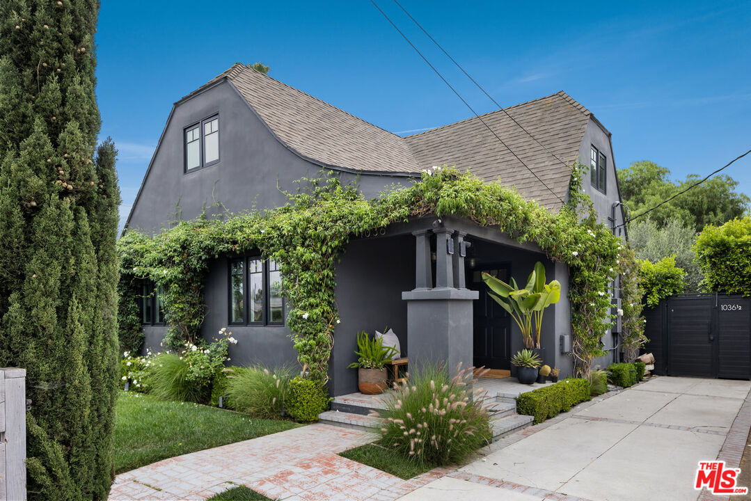 a front view of a house with plants and tree