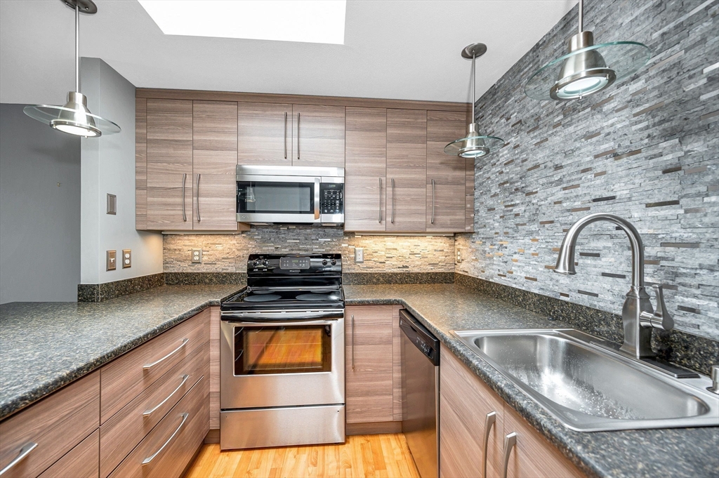 a kitchen with granite countertop a sink stainless steel appliances and cabinets