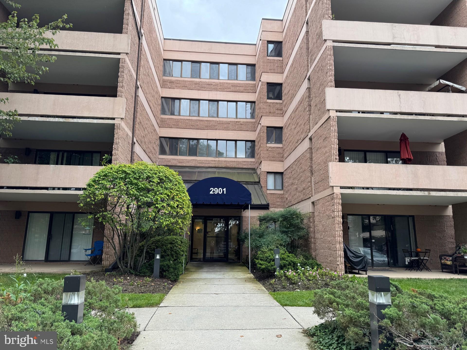 a front view of a building with a garden and plants