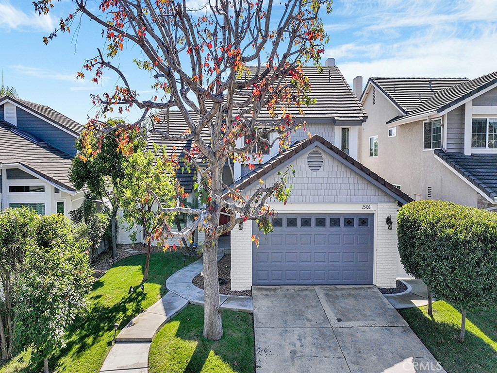 a view of a house with a small yard plants and a large tree