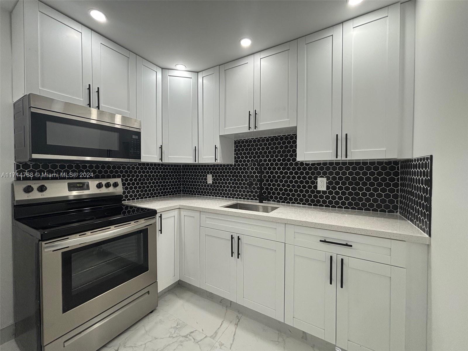 a kitchen with granite countertop white cabinets and stainless steel appliances