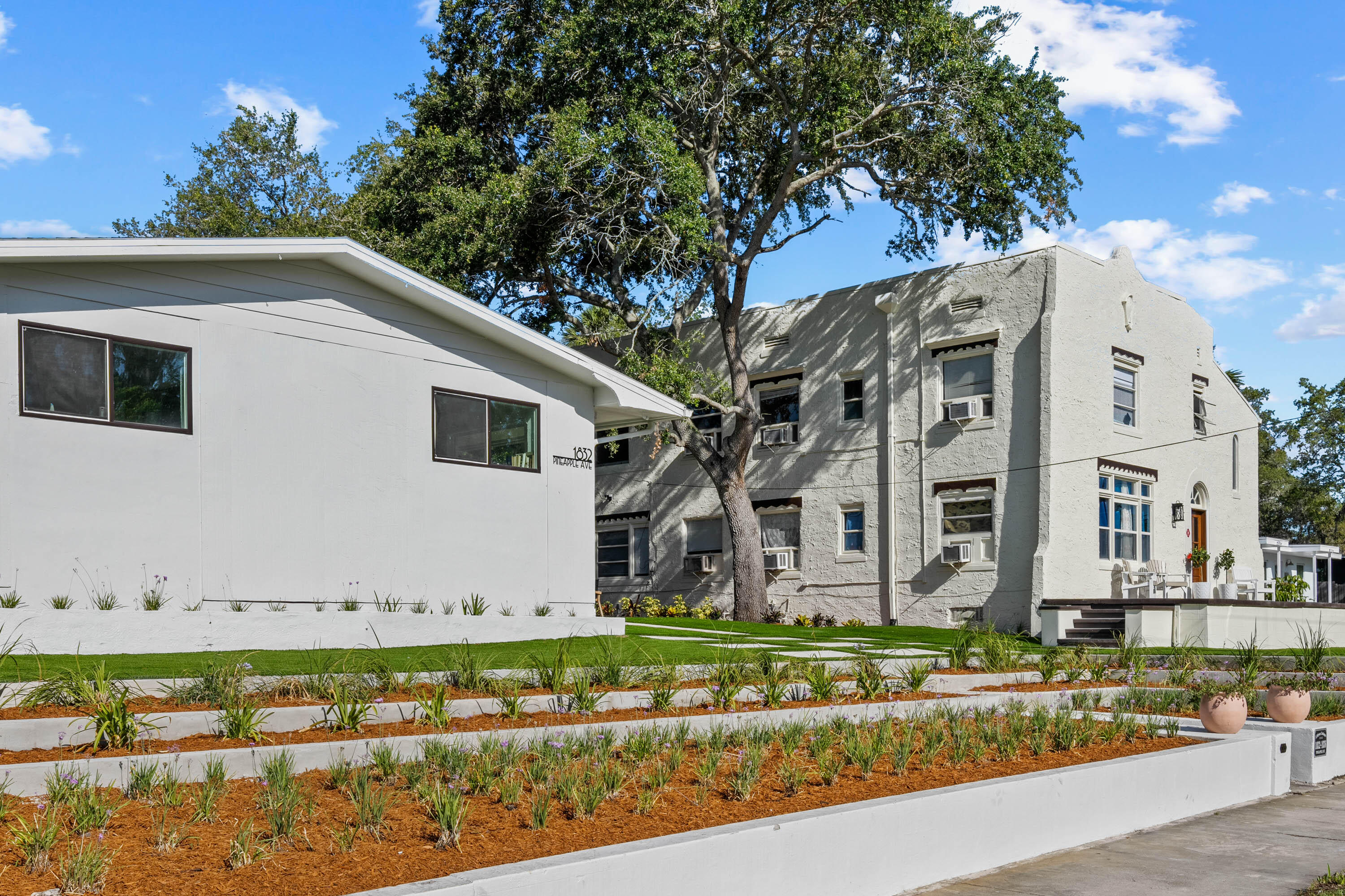 a view of a white house with a yard and plants