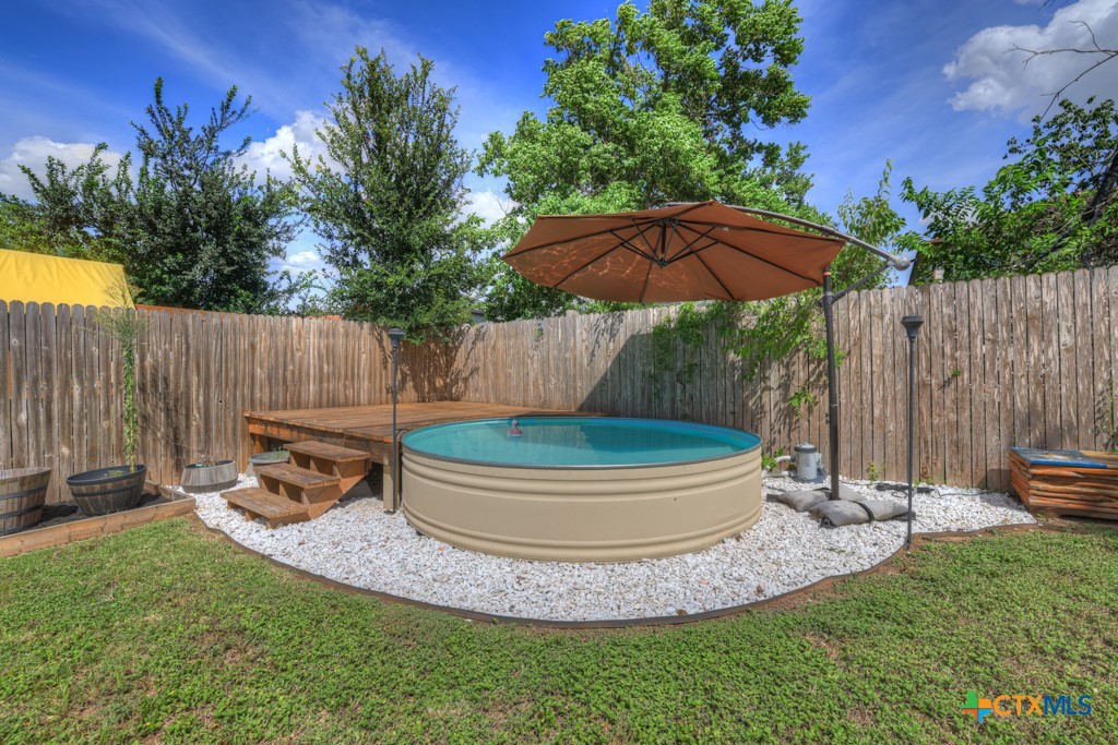 a view of a backyard with table and chairs potted plants and wooden fence