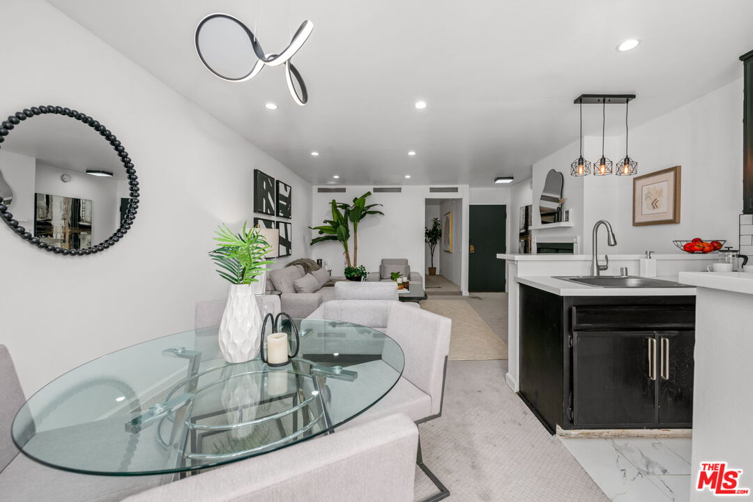 a living room with furniture a mirror and kitchen view