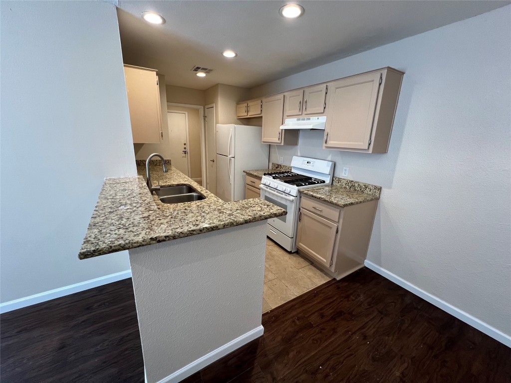 a kitchen with granite countertop a sink stove and cabinets