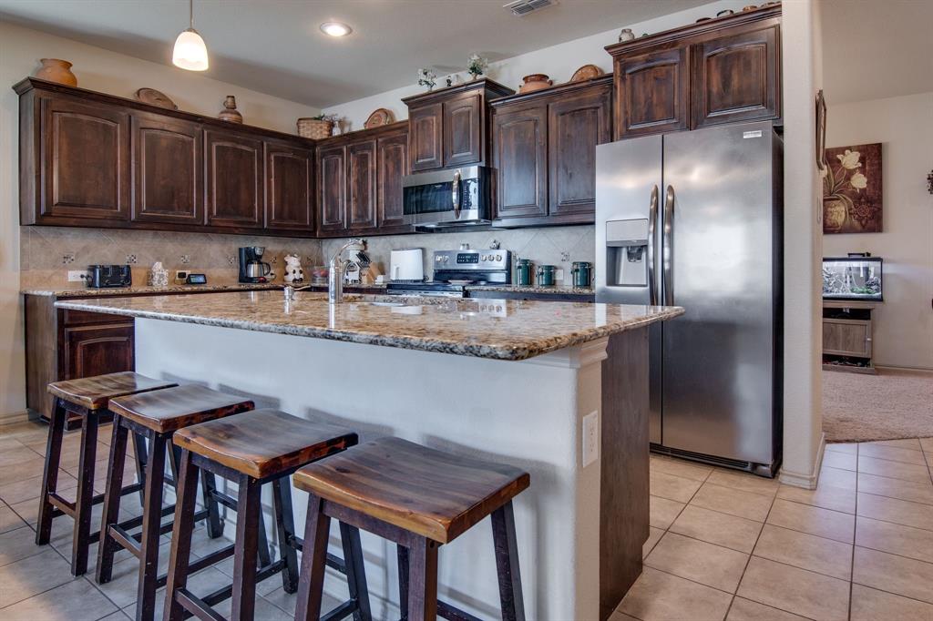 a kitchen with stainless steel appliances granite countertop a table chairs microwave and refrigerator