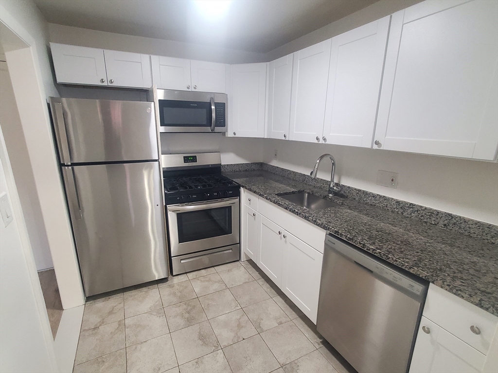 a kitchen with granite countertop a refrigerator sink and cabinets