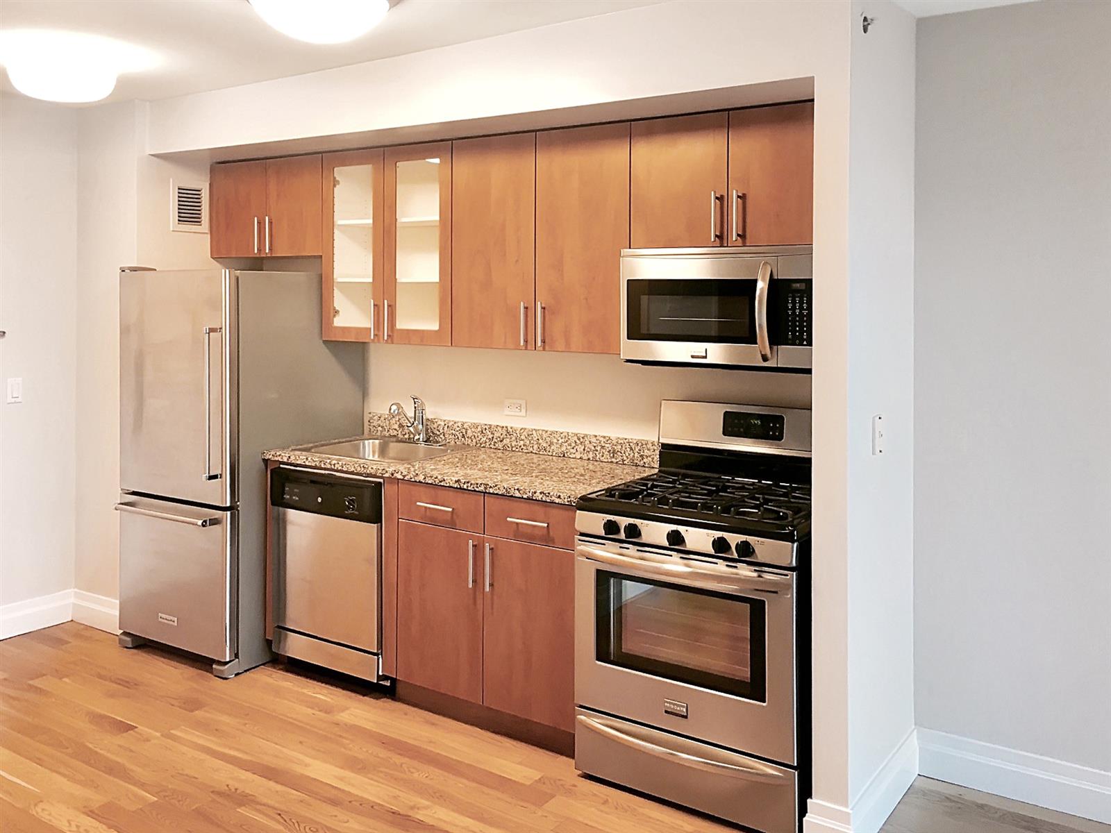 a kitchen with granite countertop a refrigerator stove and microwave