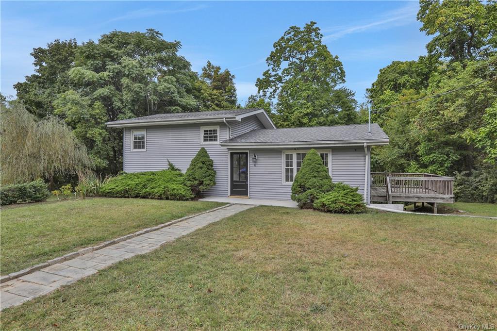 Split level home with a front yard and a deck