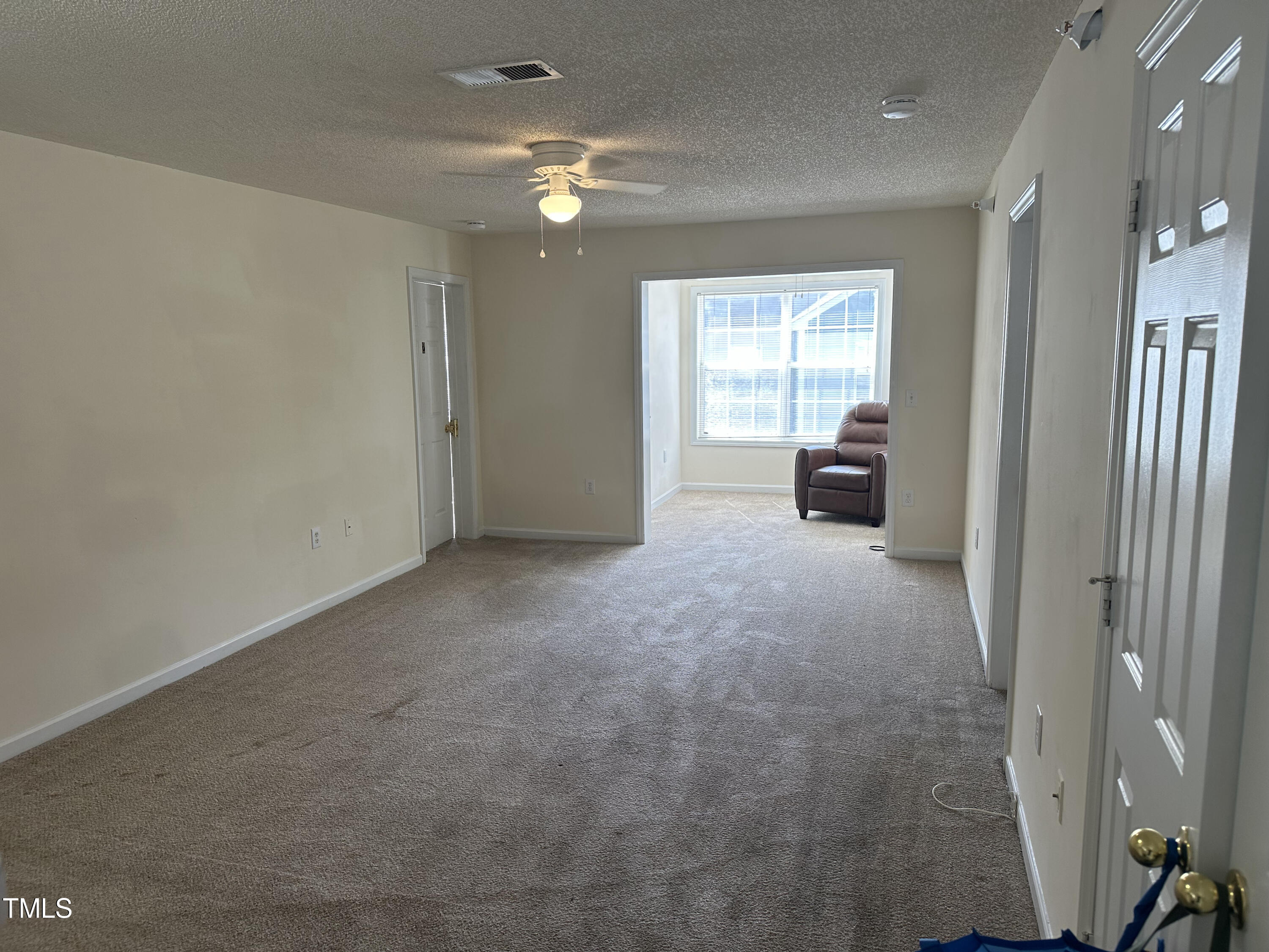 an empty room with windows and fan