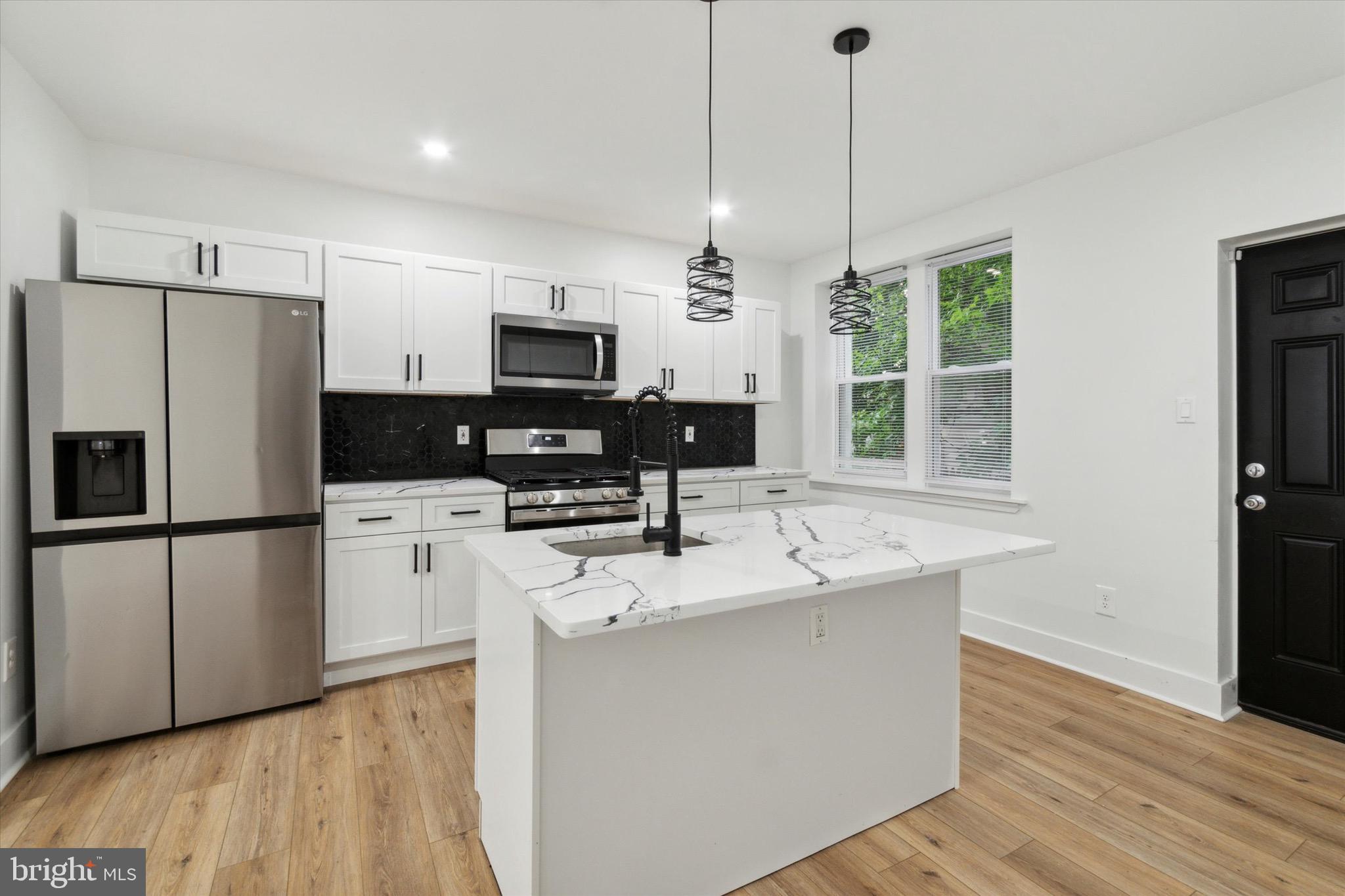 a kitchen with kitchen island a refrigerator sink and stove