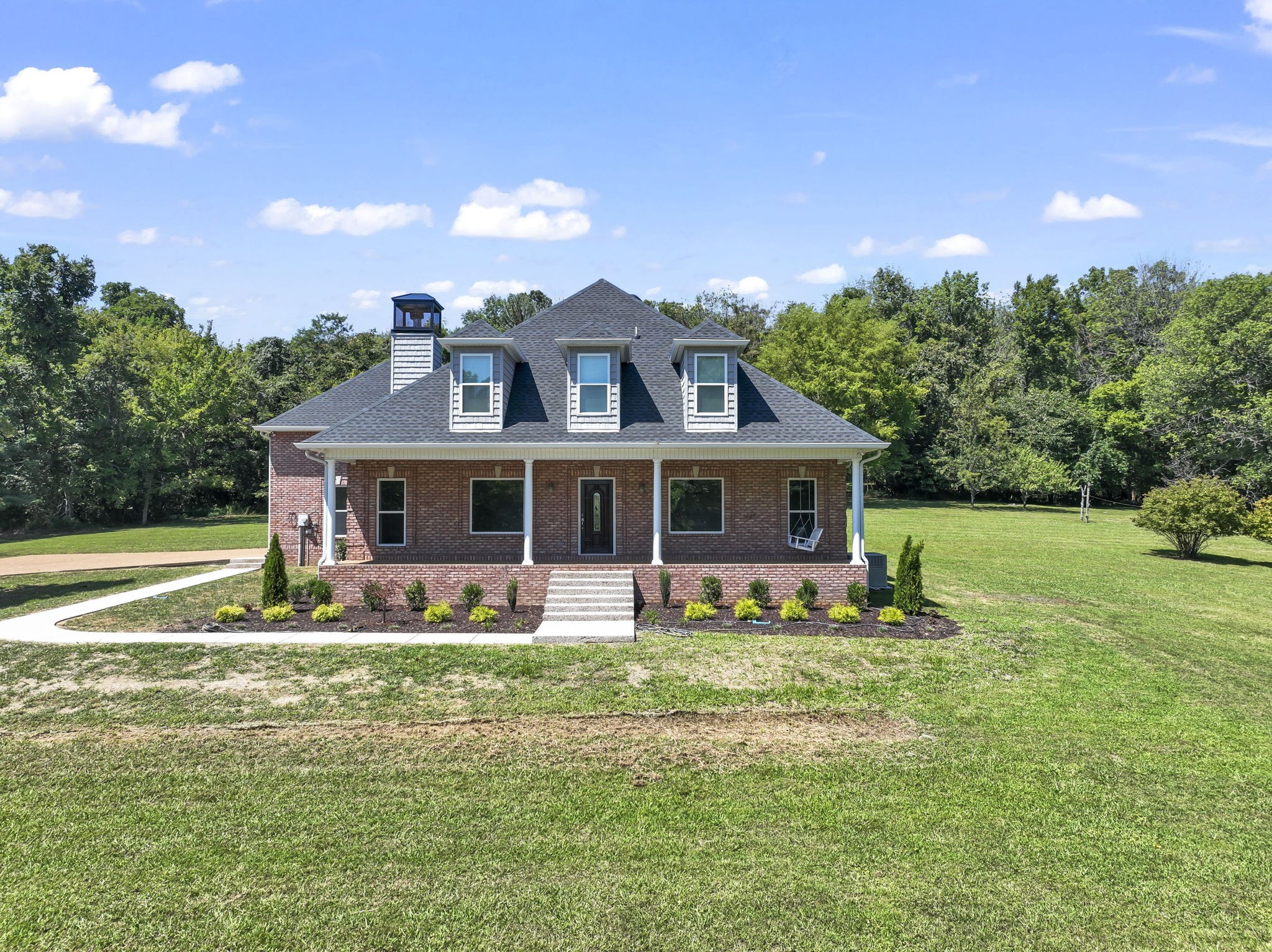 a front view of house with yard and trees in the background