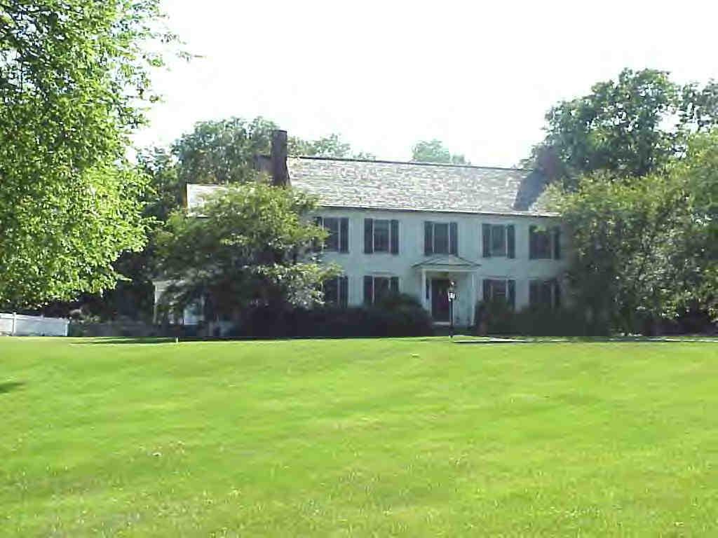 a view of house with yard and trees in the background