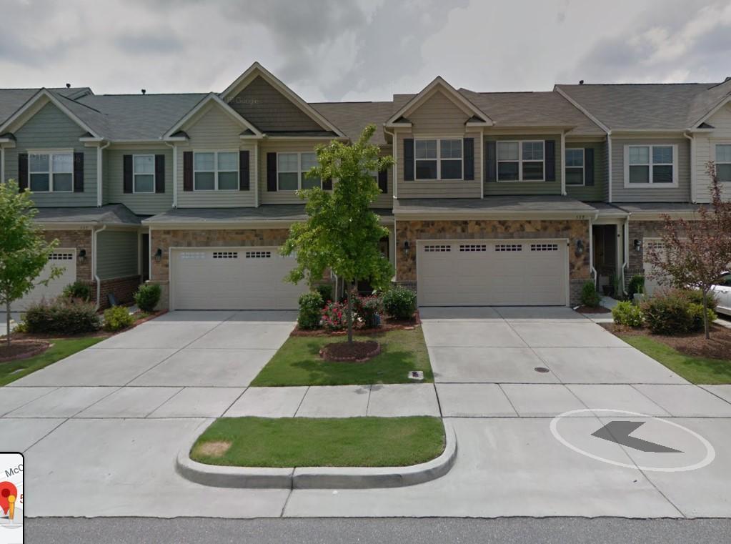 a view of a brick house with a yard and large trees