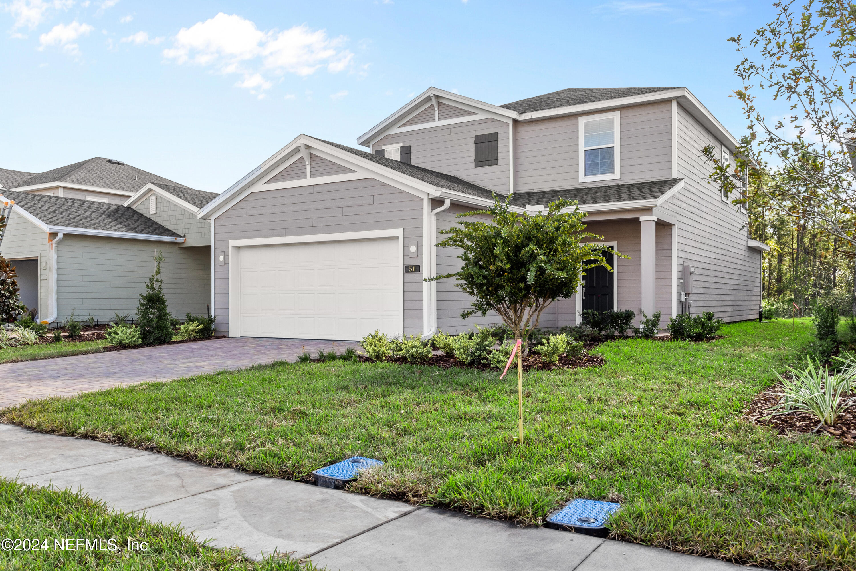 a front view of a house with a garden and trees