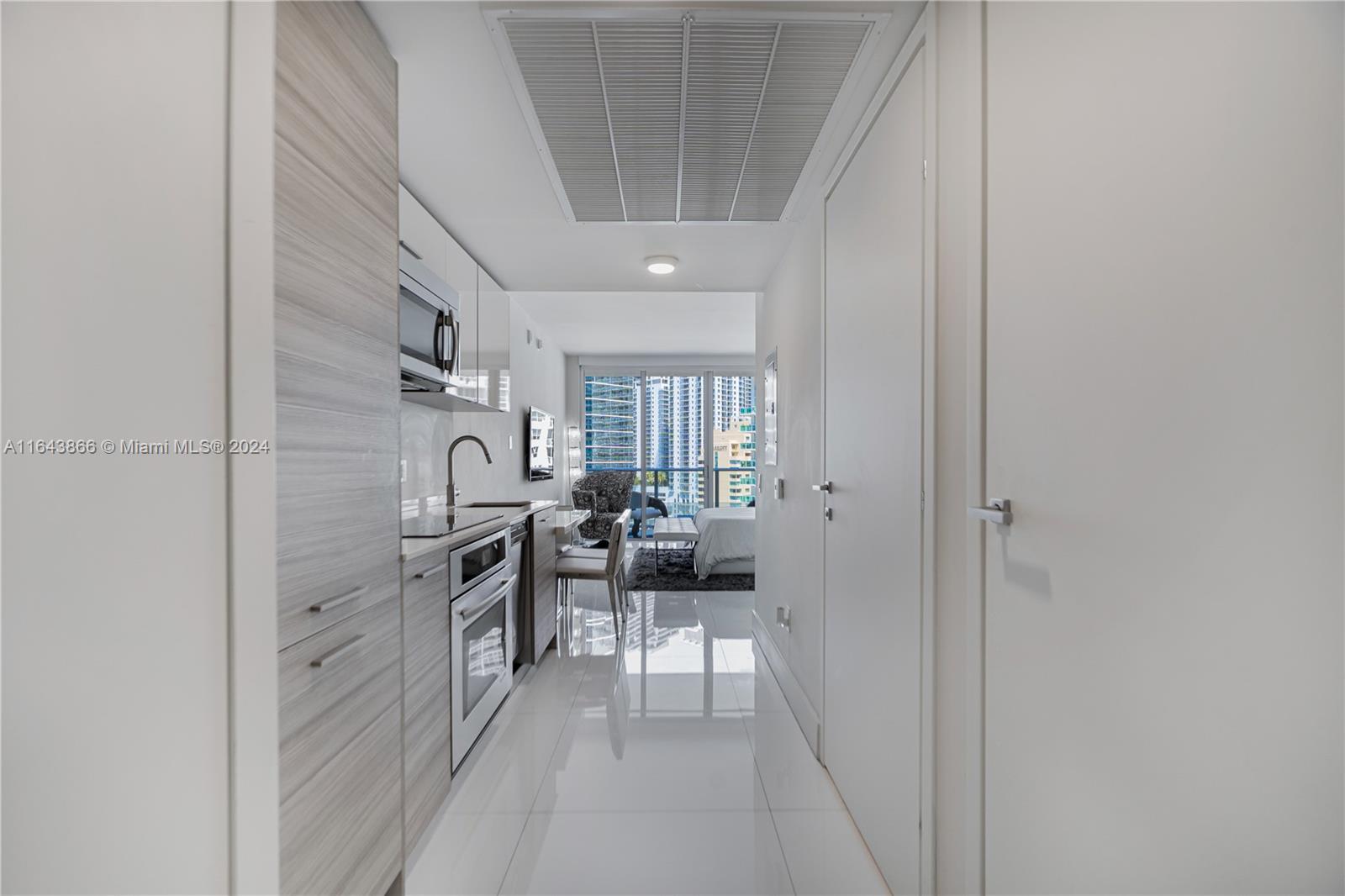 a hallway with white cabinets and stainless steel appliances