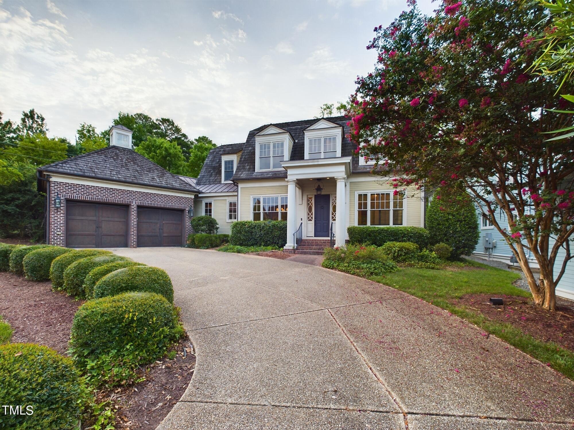 a front view of a house with a garden and trees