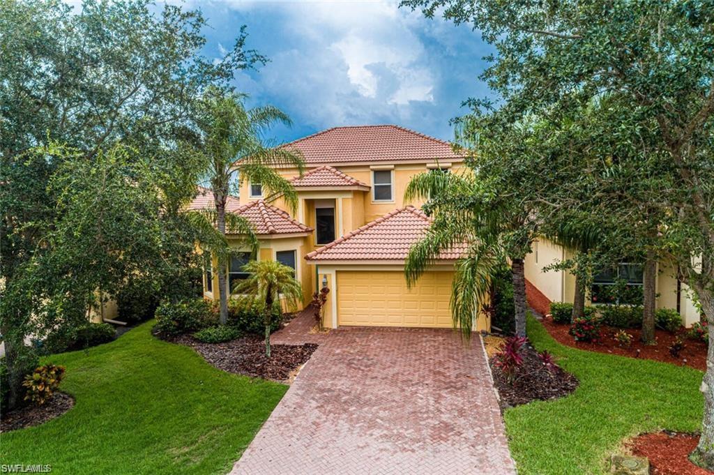 a front view of a house with a yard and a tree