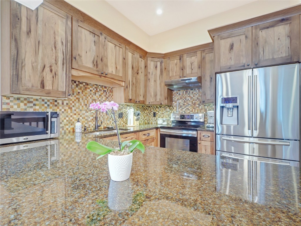 a kitchen with stainless steel appliances granite countertop a refrigerator sink and cabinets