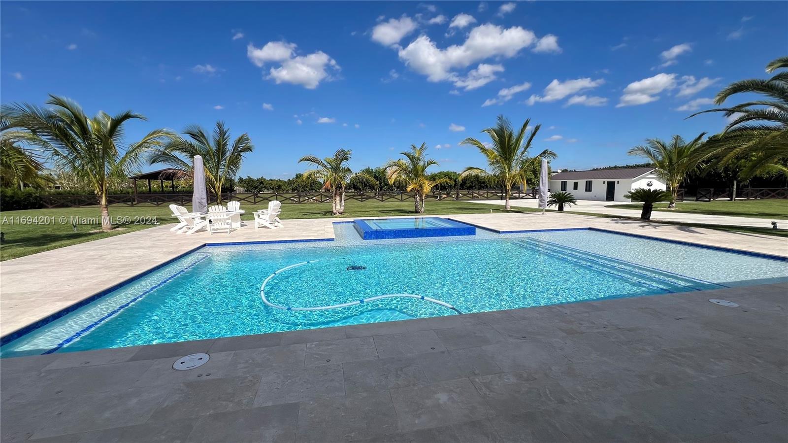 a view of yard with swimming pool outdoor seating and trees in the background