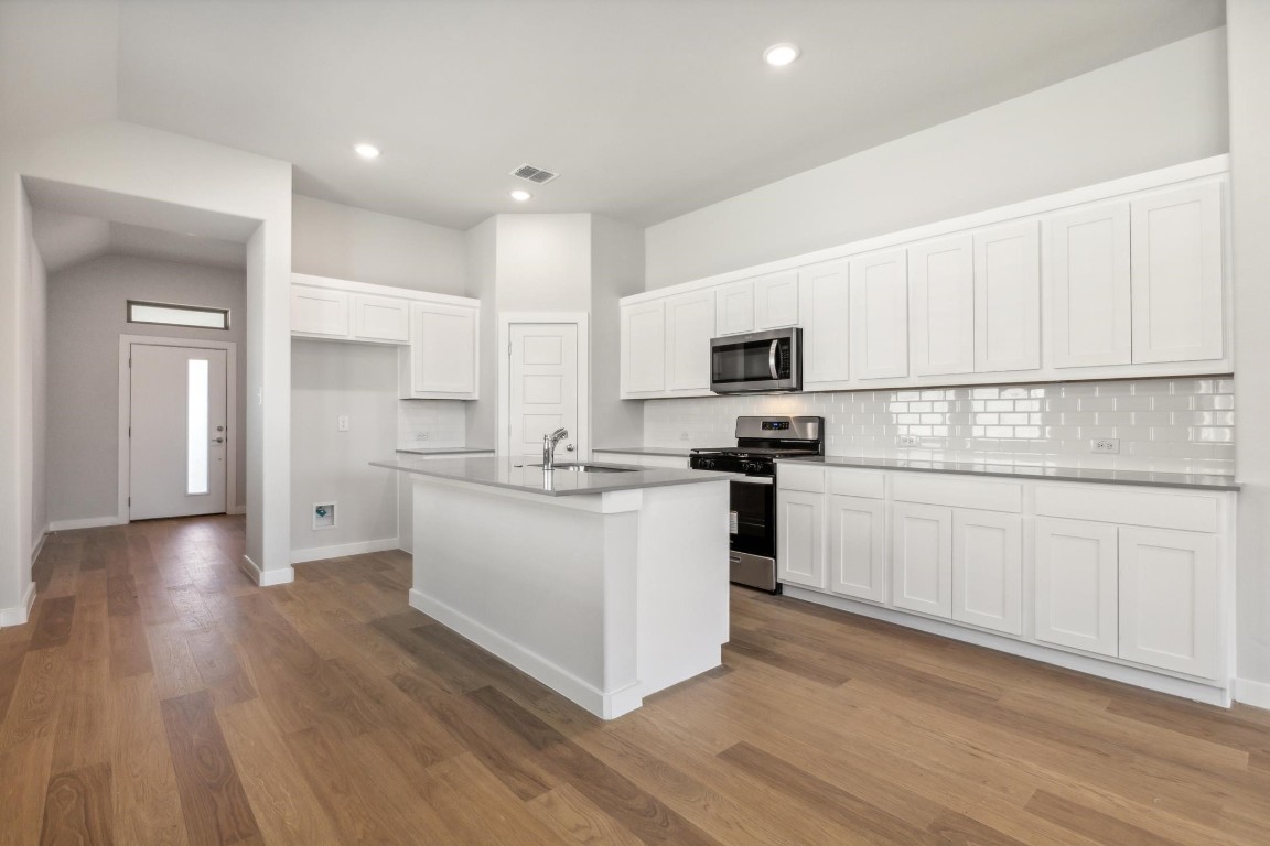 a kitchen with white cabinets and appliances