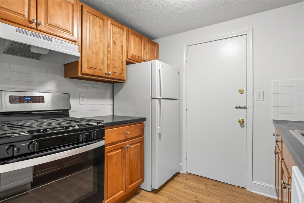 a kitchen with stainless steel appliances granite countertop a refrigerator and a stove top oven