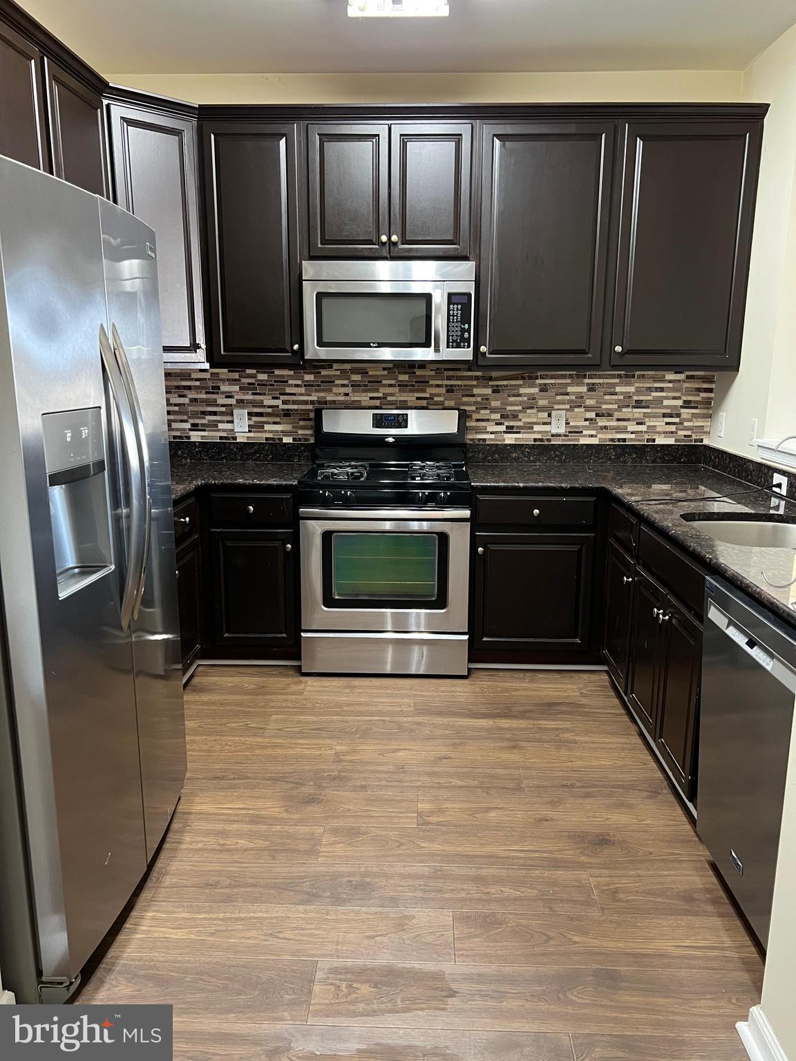 a kitchen with granite countertop a refrigerator stove and microwave