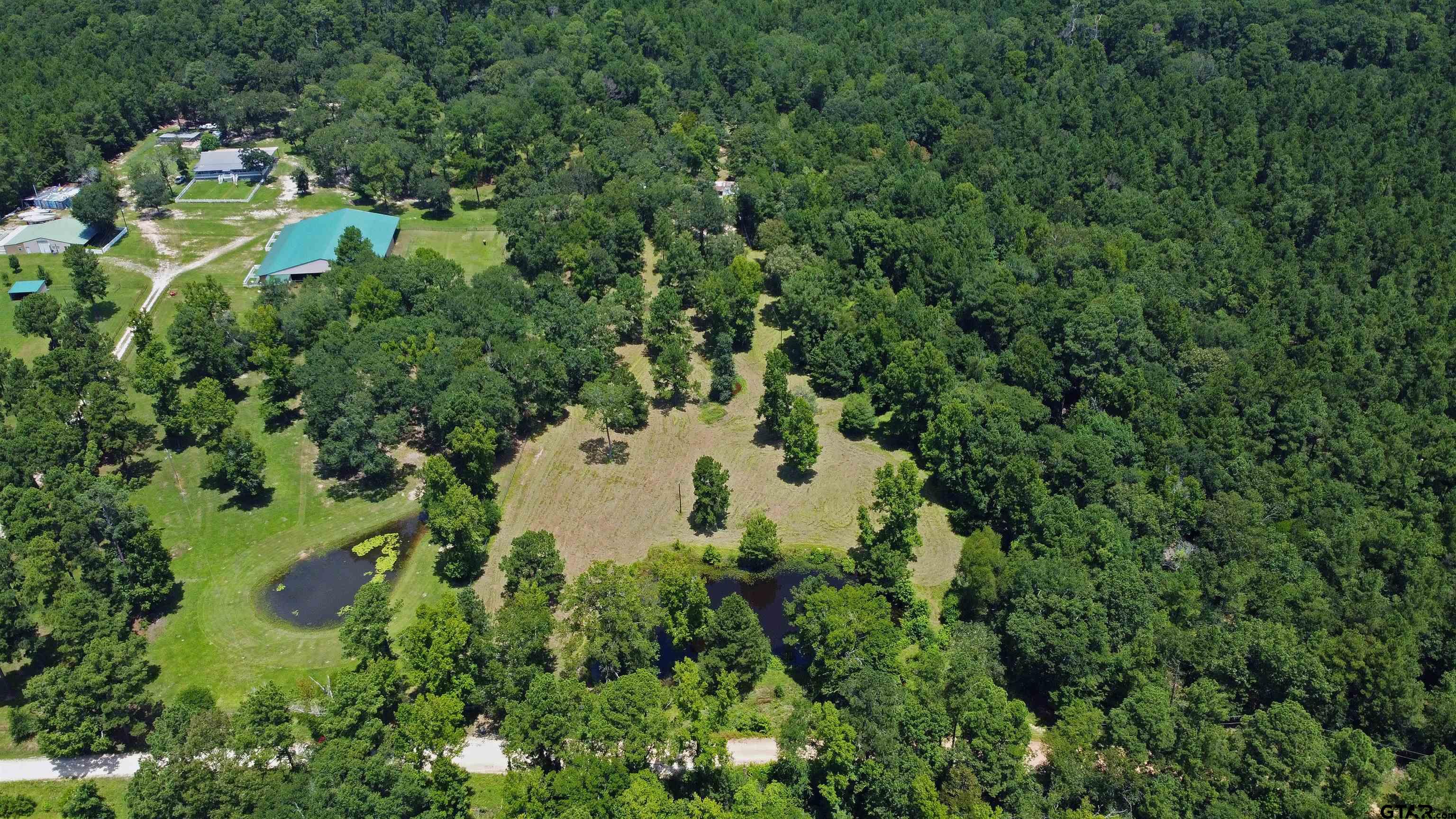 an aerial view of residential house with outdoor space and trees all around