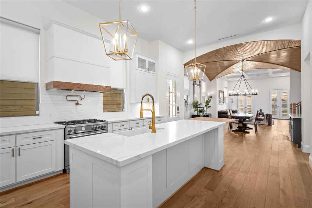 a kitchen with a sink a stove and chairs with wooden floor