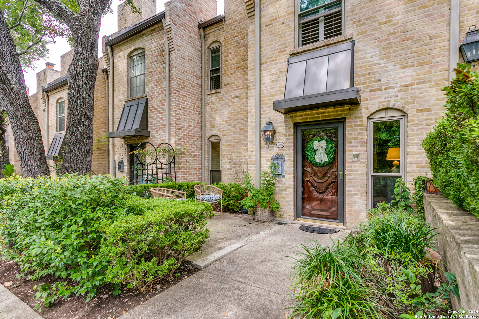 a view of a brick house with a large windows and flower plants