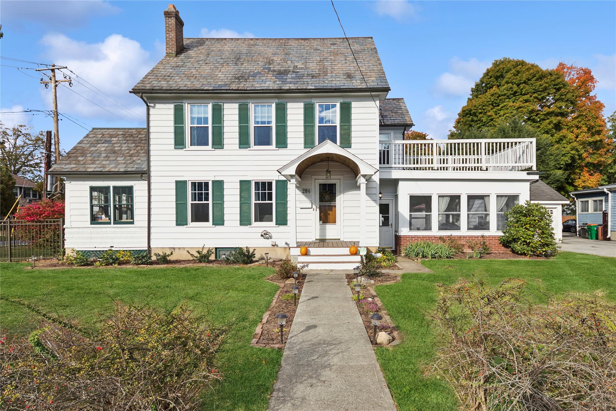 Colonial house featuring a balcony and a front lawn