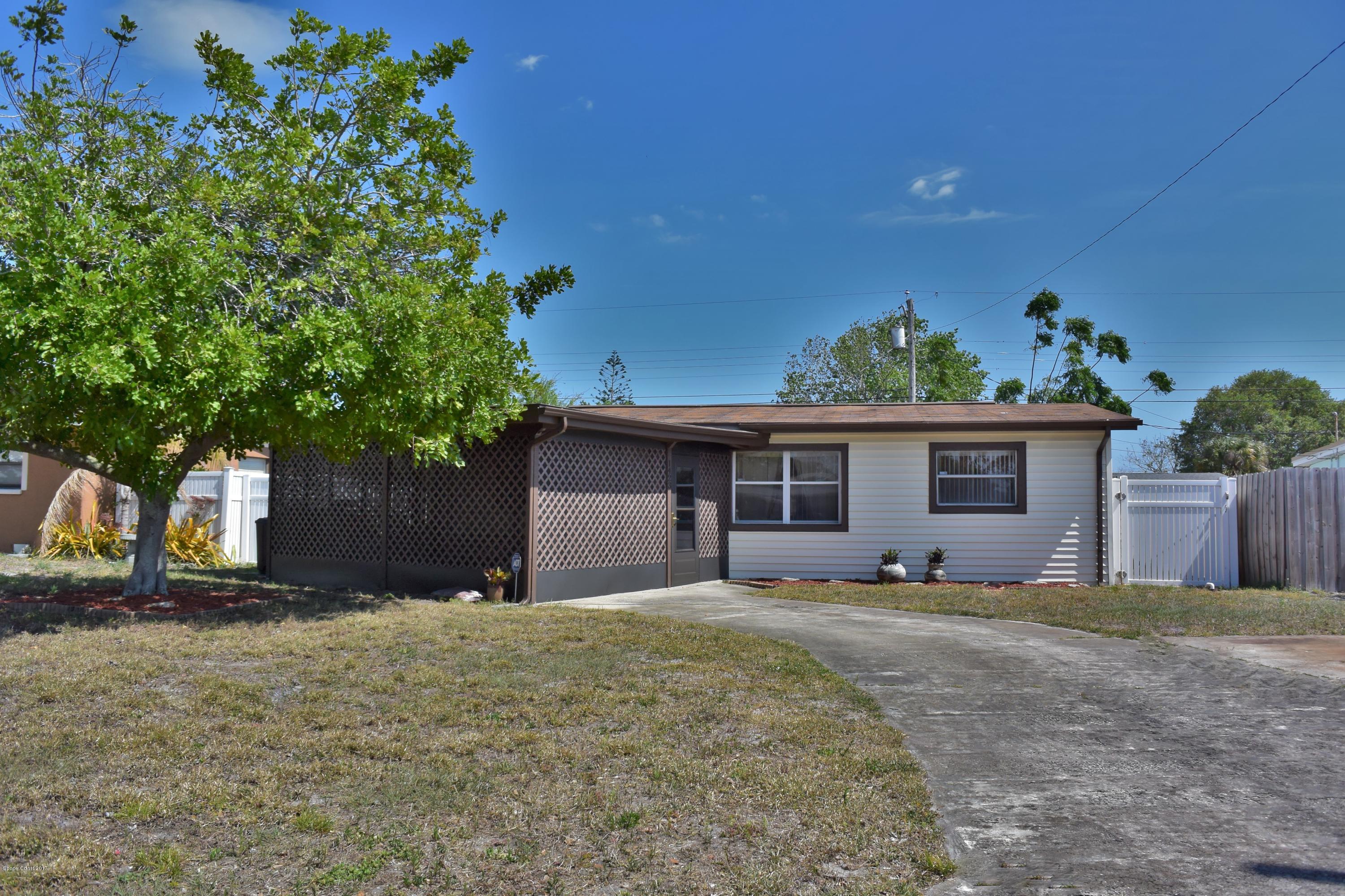 a front view of house with yard and trees in the background