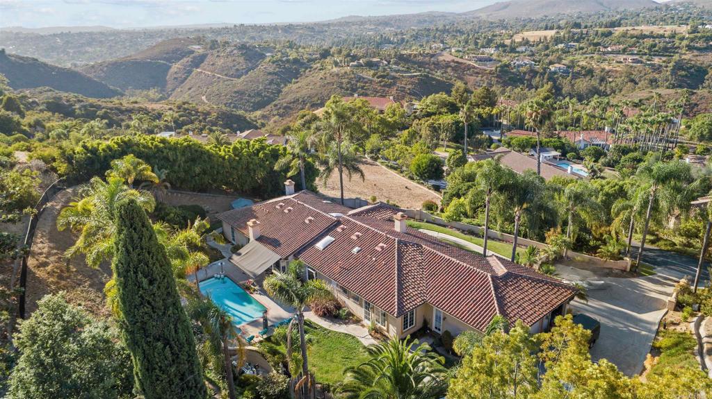 an aerial view of a house with a yard and mountain view in back