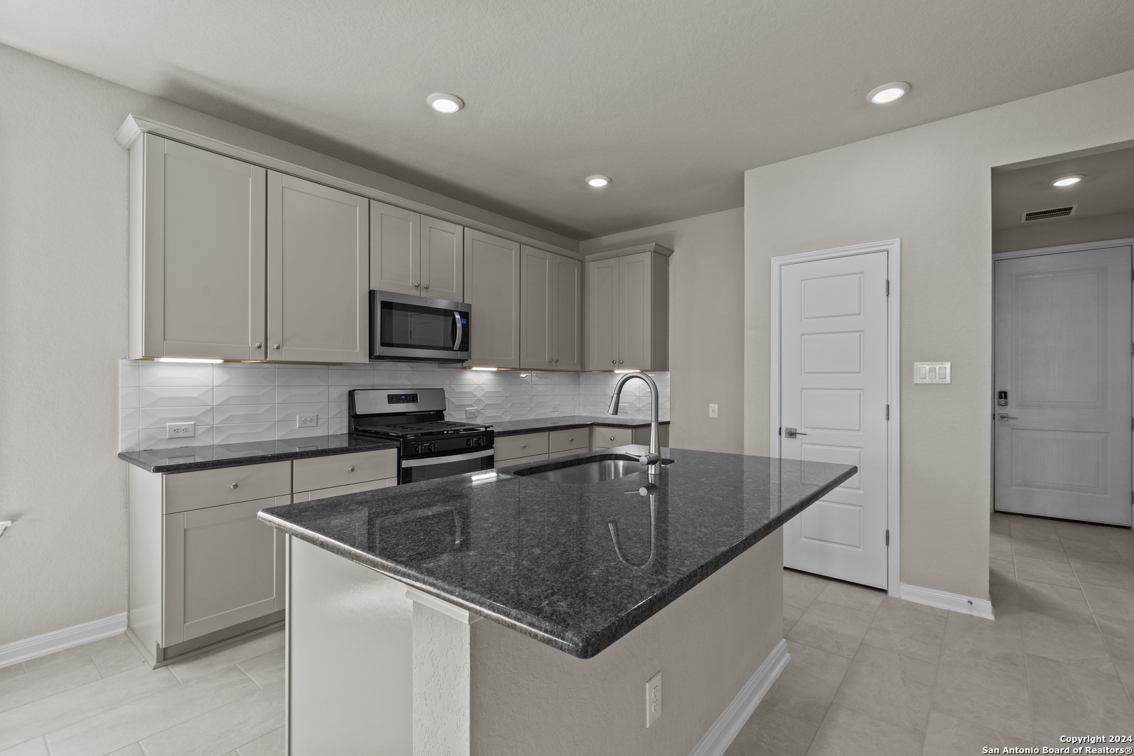 a kitchen with granite countertop a sink a stove and refrigerator