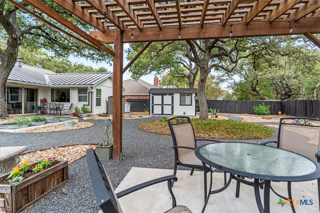 a view of a patio with couches table and chairs under an umbrella with a small yard