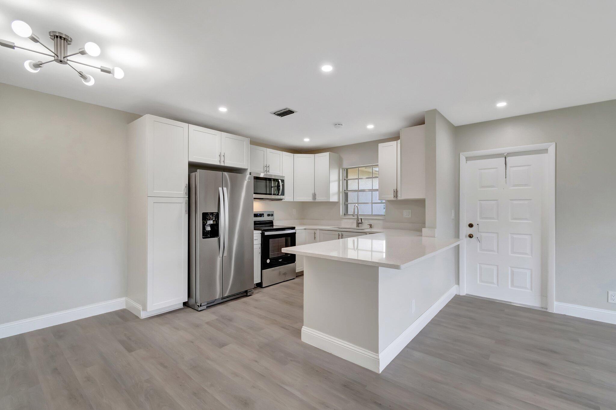 a view of kitchen with refrigerator cabinets and wooden floor