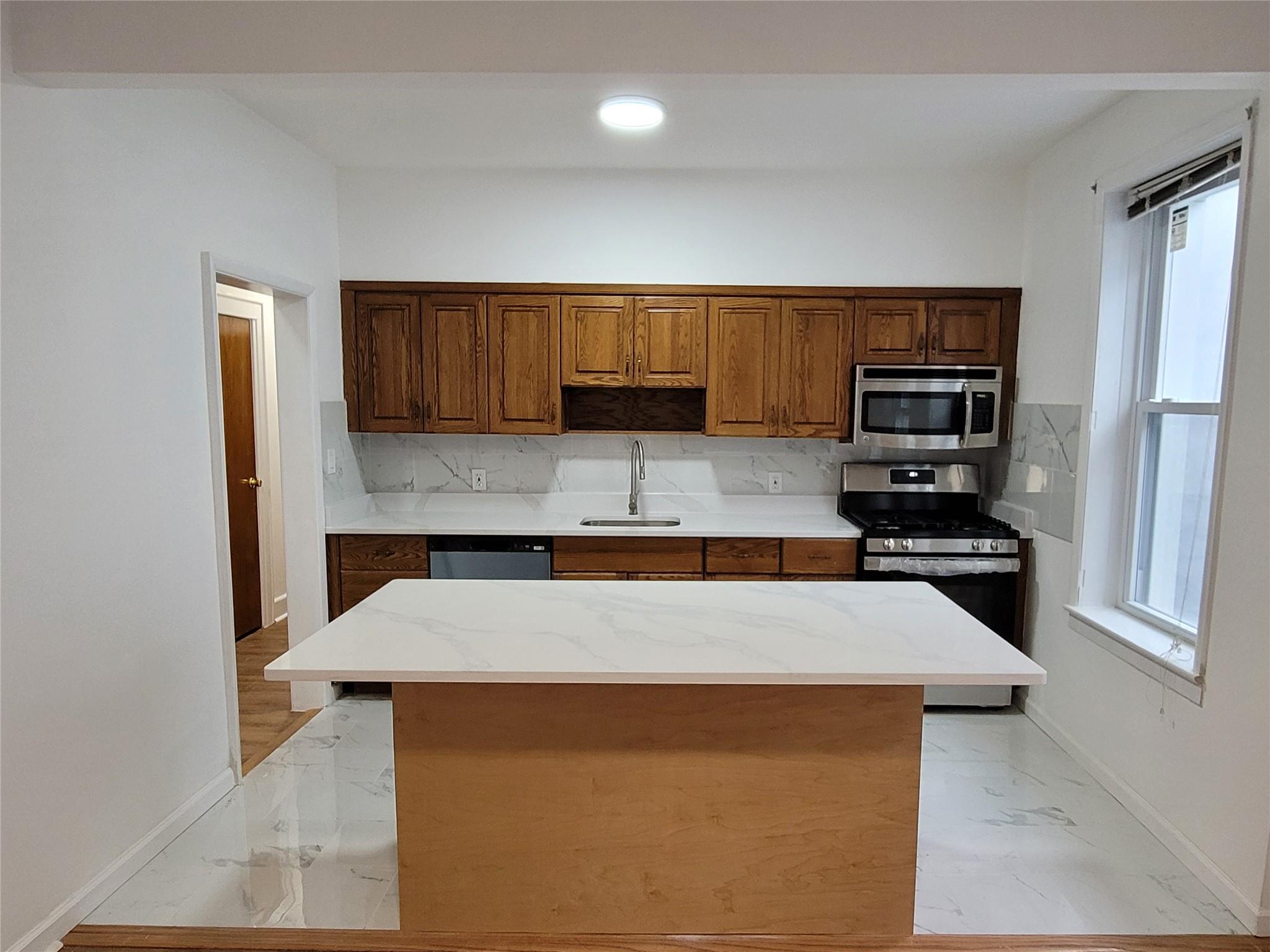 Kitchen featuring backsplash, sink, a kitchen island, and appliances with stainless steel finishes