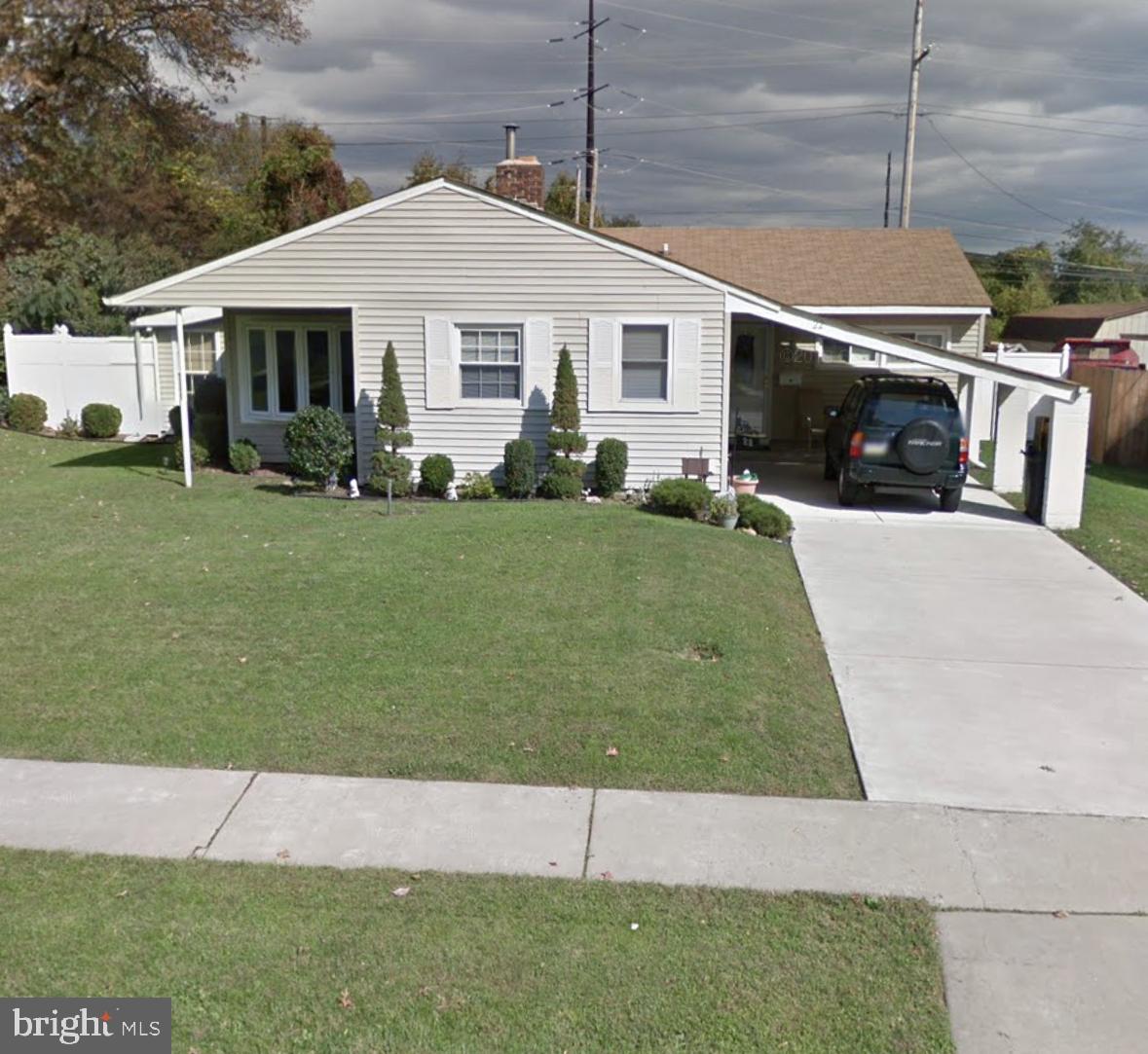 a view of a white house next to a yard with big trees